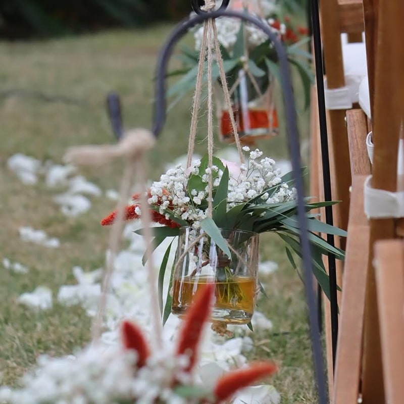 Décoration Rustique Mariage : Fleurs suspendues et allée Décoration rustique de mariage : bouquets de gypsophile et feuillage dans des verres suspendus par de la ficelle de jute le long d'une allée de pétales blancs.